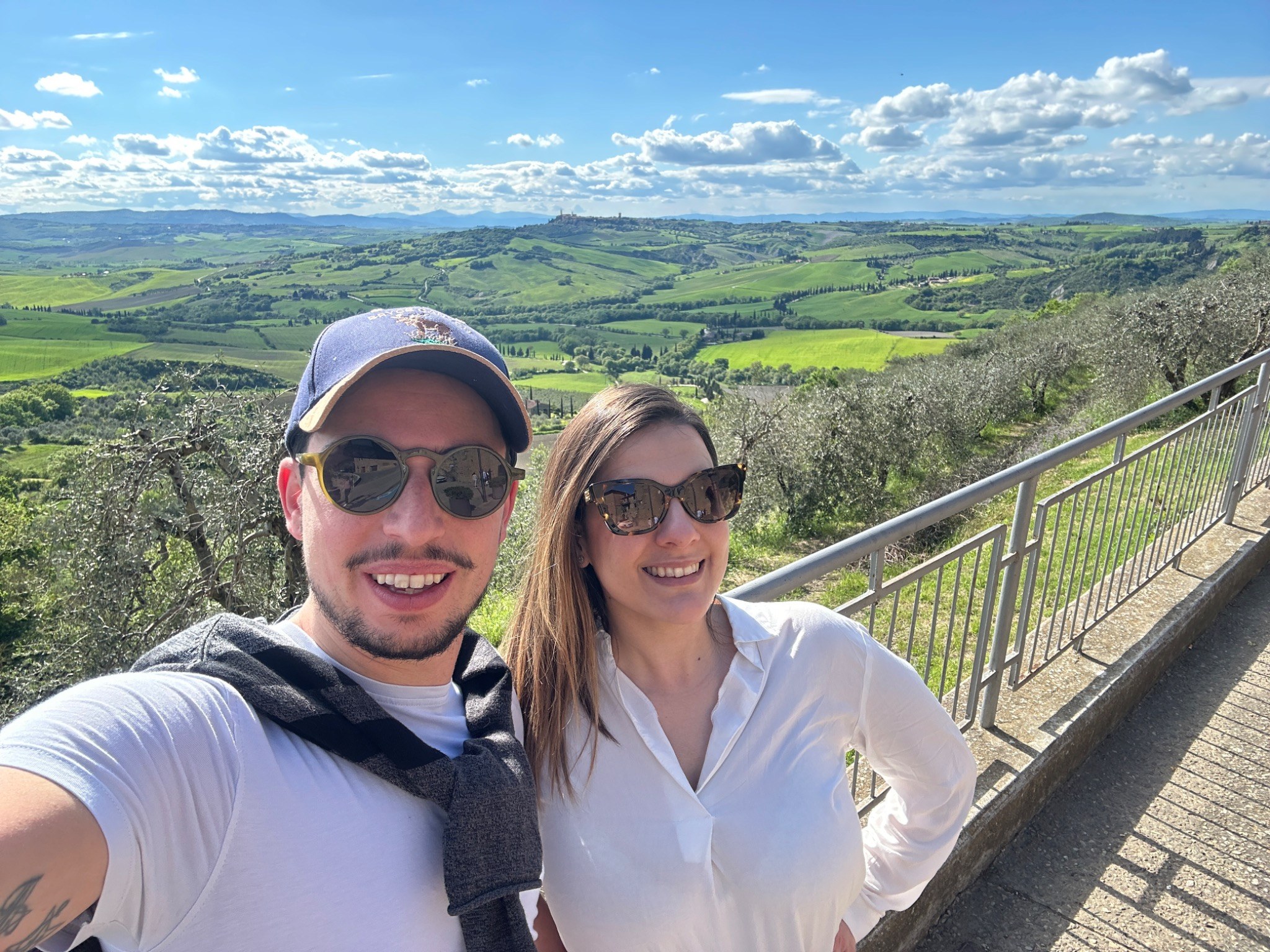Francesco Pio e Ilaria in viaggio, con panorama collinare sullo sfondo.